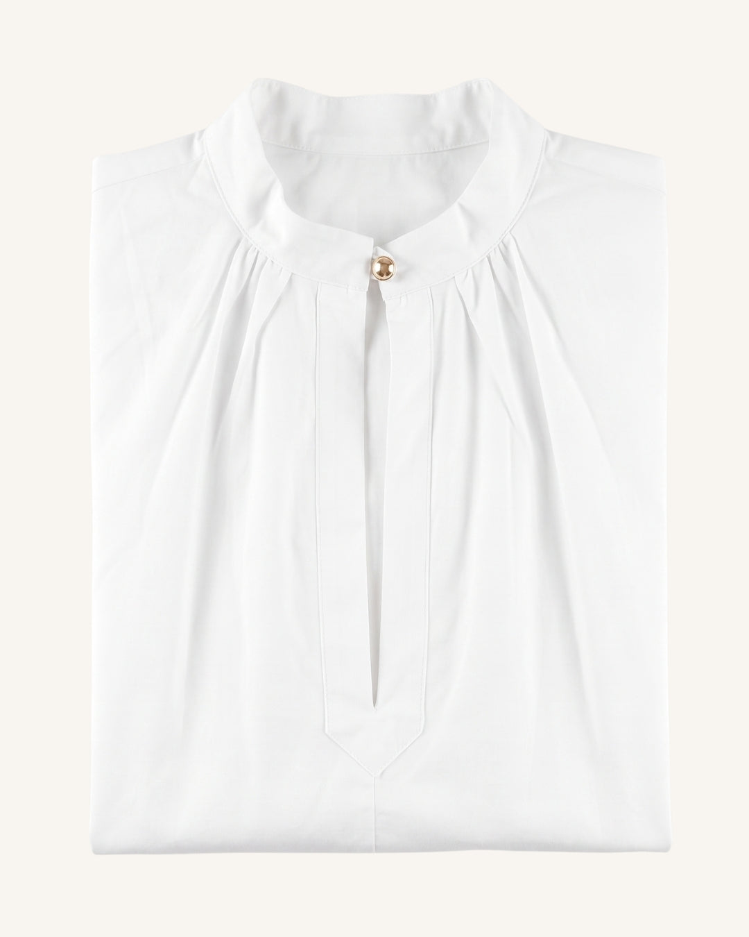 A folded white blouse with a high gathered collar and a small gold button at the neckline, shown on a plain light beige background.
