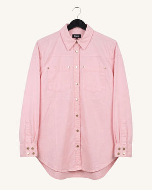 A light pink long-sleeve button-up shirt with two chest pockets and decorative metal snap details, hanging on a black hanger against a plain off-white background.