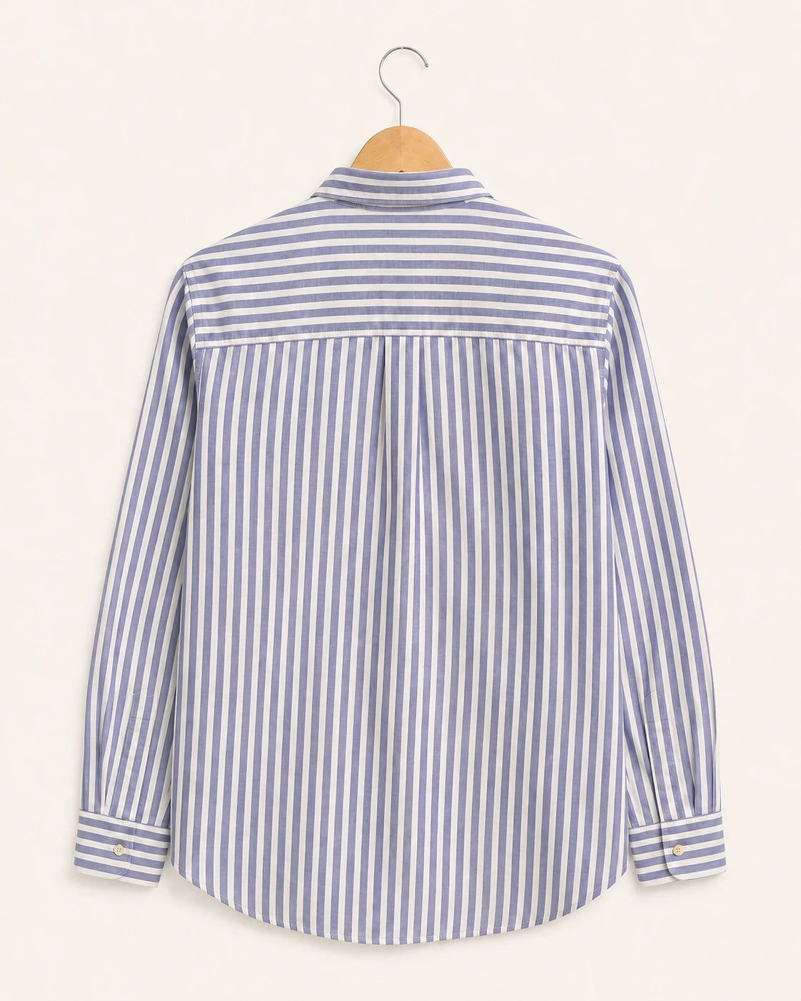 A long-sleeve striped button-up shirt hanging on a wooden hanger against a light cream background. The shirt features vertical stripes in blue and white, with a matching blue horizontal stripe panel across the upper back.