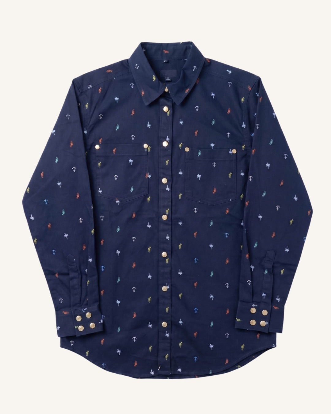 A navy blue long-sleeve button-up shirt with a small repeating anchor pattern in red, blue, and white, displayed flat against a light cream background.