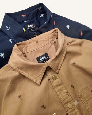 Two Bani short-sleeve button-up shirts with small palm tree prints, shown overlapping. The front shirt is a warm tan/khaki color, and the shirt behind it is navy blue.