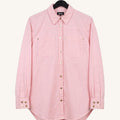 A light pink long-sleeve button-up shirt with two chest pockets and decorative metal snap details, hanging on a black hanger against a plain off-white background.