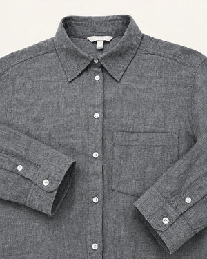 A close-up of a dark gray textured linen shirt with a pointed collar, button-down front, and a chest pocket, laid flat against a light off-white background.