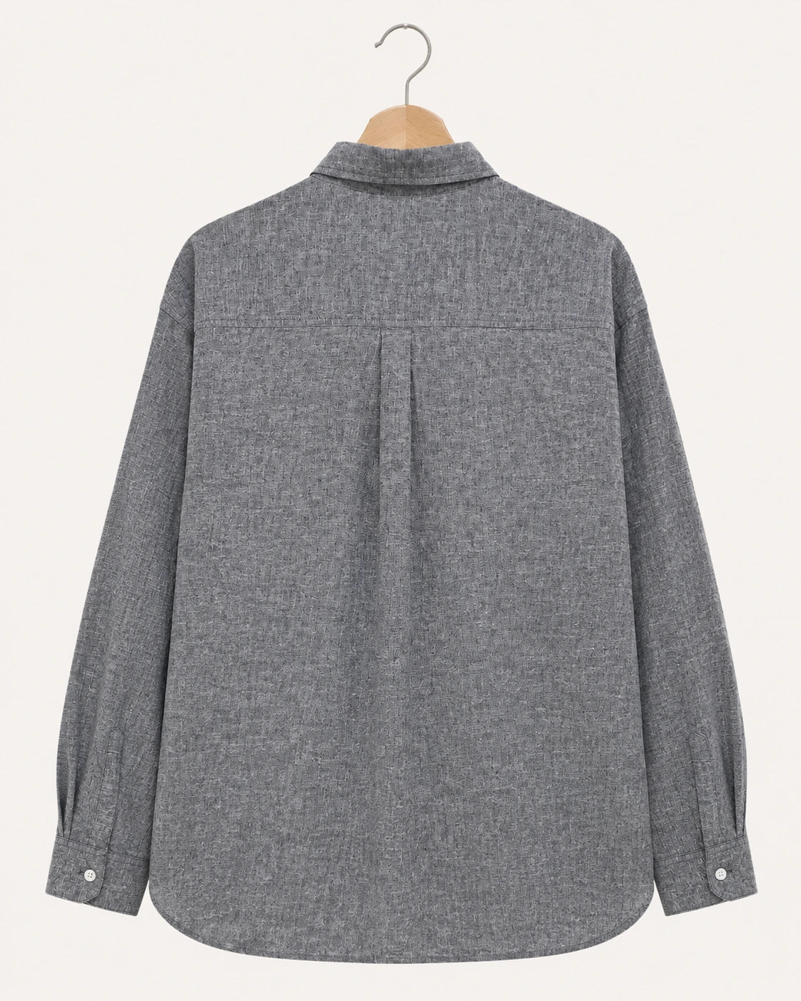 A gray textured long-sleeve button-up shirt shown from the back, hanging on a wooden hanger against a light cream background.