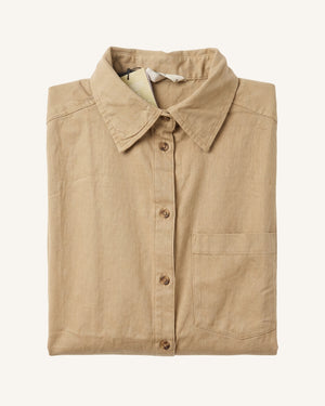 A folded tan linen button-up shirt with a classic collar and a single chest pocket, displayed on a clean off-white background.